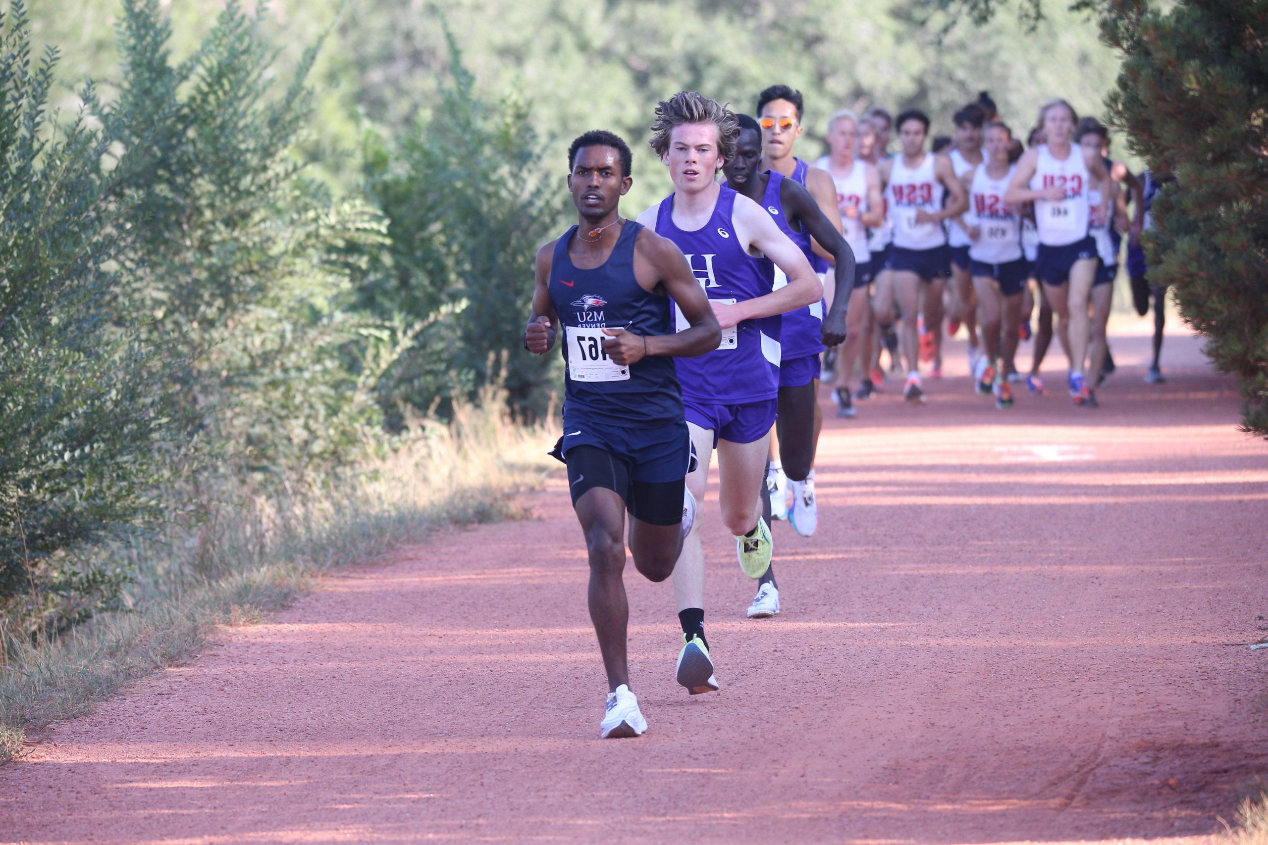 Men's cross country runner Yoni Kefle leads a large pack of runners at a race in 2021.