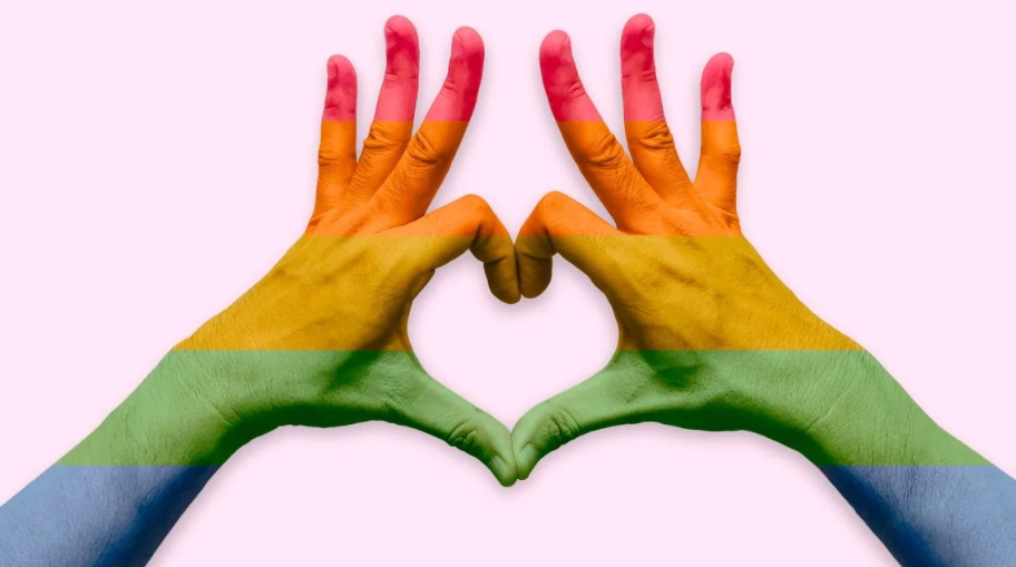 Rainbow hands making heart shape.
