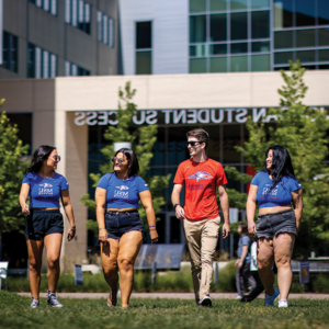 Four students walking on the lawn in front of the Jordan Student Success Building