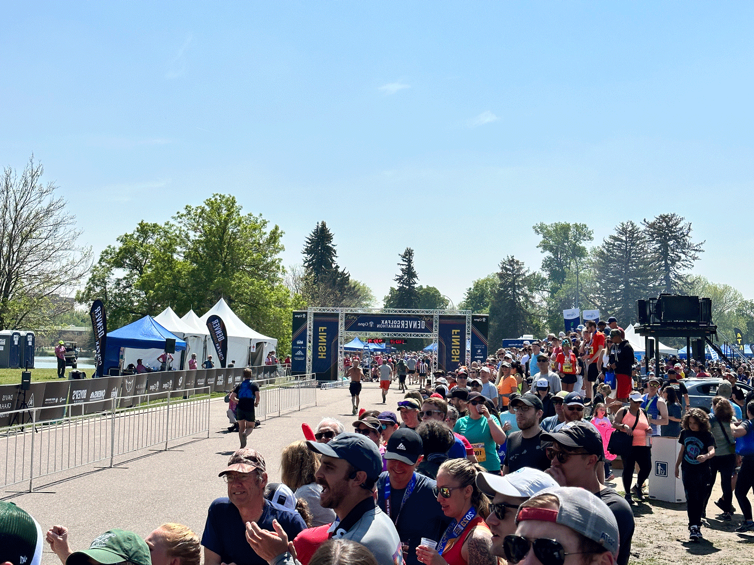 Runners crossing the finish line in front of a large crowd at the 2023 Denver Colfax Marathon